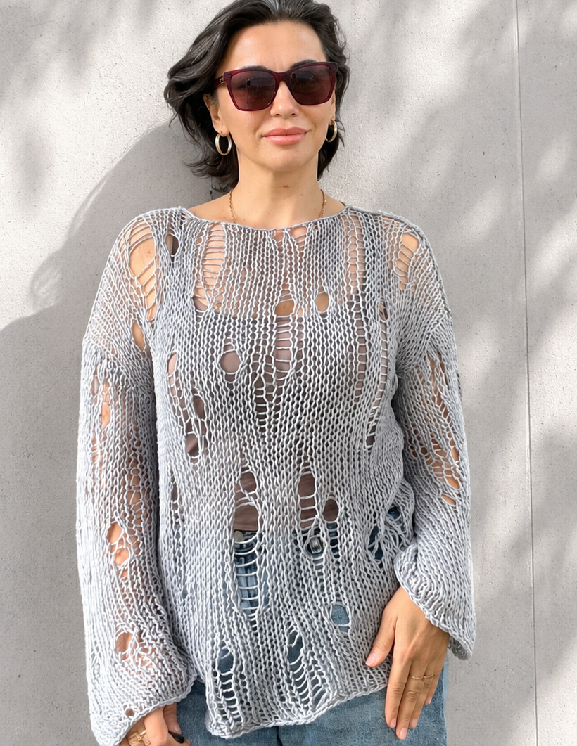 Front view of an oversized distressed cotton knit sweater in soft grey blue color with airy open-knit texture and relaxed luxury summer styling
